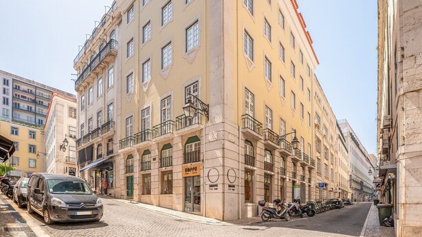 Vista de la calle de un edificio con varios pisos, balcones y un letrero que dice 'KOPPU'.