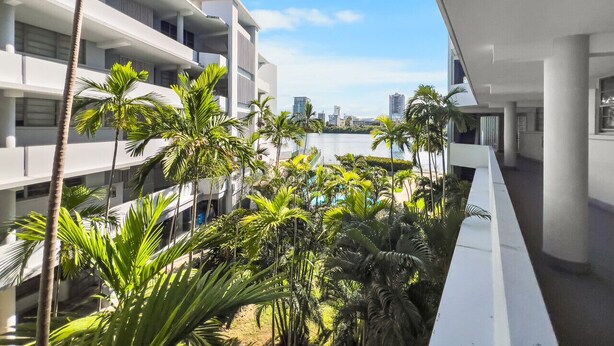 A modern hotel with multiple floors, a pool area with palm trees, and a view of the city skyline. - Condado Studio w/Pool  • Walk to Beach & Dining (San Juan)