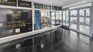 A modern interior with a black and white color scheme, featuring a coffee specialty section, a sign for condominium guests, and a QR code for a loyalty program. - Condado Studio w/Pool  • Walk to Beach & Dining (San Juan)
