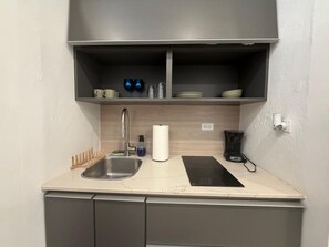 Une petite cuisine équipée d’un évier, d’une machine à café et d’un distributeur d’essuie-tout.