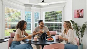 A dining area with a round table, three chairs, and a potted plant.