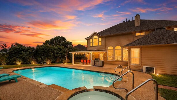 A swimming pool with a hot tub, outdoor seating, and a covered patio area.