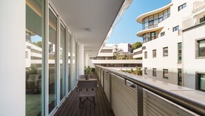 A balcony with a wooden floor and a table with chairs.