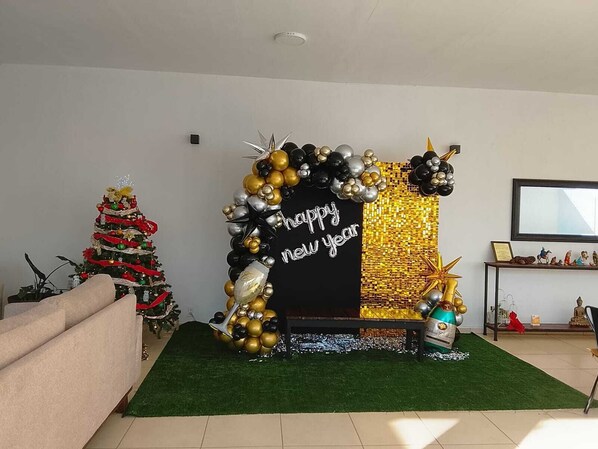 Un salon décoré d’un sapin de Noël, d’une décoration noire et dorée pour le Nouvel An, et d’un téléviseur à écran plat posé sur un meuble.