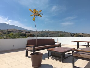 A terrace with a sofa, a table, and a potted plant, overlooking a hilly landscape. - Los Laureles Country House with a Swimming Pool in Tequila (10 min. from Cantaritos El Güero) (Tequila)