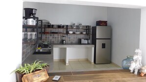 A modern kitchen with a built-in stove, a refrigerator, and a microwave. There are shelves with kitchenware and a potted plant. - Los Laureles Country House with a Swimming Pool in Tequila (10 min. from Cantaritos El Güero) (Tequila)