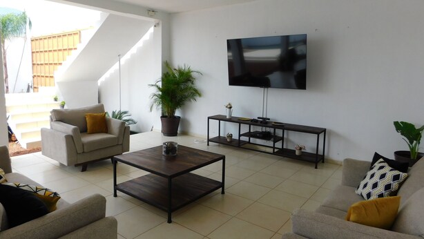 A modern living room with a sofa, coffee table, TV, and potted plants. - Los Laureles Country House with a Swimming Pool in Tequila (10 min. from Cantaritos El Güero) (Tequila)