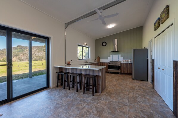 A modern kitchen with a large island, bar stools, a built-in oven, and a refrigerator.