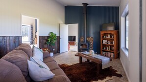 A cozy living room with a brown sofa, a coffee table, a fireplace, and a bookshelf.