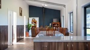 A modern dining area with a large table, chairs, ceiling fans, and a view of the outdoors.