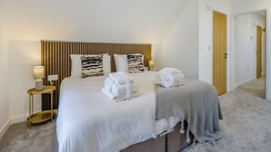 A neatly made bed with towels, a bedside lamp, and a wooden headboard in a hotel room. - 3 bedroom accommodation in East Firsby (East Firsby)