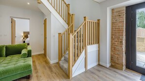 A staircase with wooden railings, a green sofa, and a brick wall. - 3 bedroom accommodation in East Firsby (East Firsby)