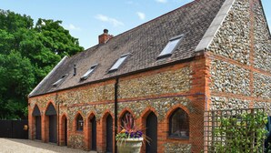 A stone building with a sloped roof, arched windows, and a gravel driveway.