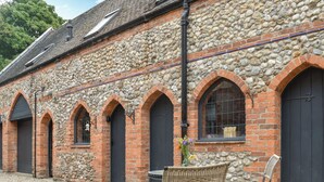 A stone building with arched windows and doors, a gravel courtyard, and outdoor furniture.