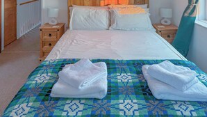 A neatly made bed with white linens, two bedside tables with lamps, and a patterned bedspread. - 3 bedroom accommodation in Aberystwyth (Aberystwyth)