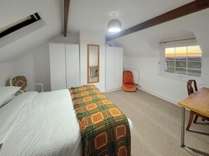 A bedroom with a bed, a chair, a table, a wardrobe, a radiator, and a window with a view. - 3 bedroom accommodation in Aberystwyth (Aberystwyth)