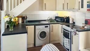 A compact kitchen with a washing machine, microwave, and toaster.
