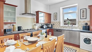 A modern kitchen with a dining area, stainless steel appliances, and a large window. - 3 bedroom accommodation in Roker, near Sunderland (Roker, near Sunderland)