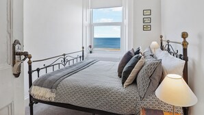 A bedroom with a bed, a bedside lamp, a view of the sea, and a window. - 3 bedroom accommodation in Roker, near Sunderland (Roker, near Sunderland)
