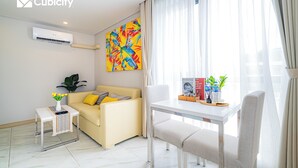 Ein modernes Wohnzimmer mit einer Couch, einem Couchtisch, einem Beistelltisch mit Blumen und einem farbenfrohen abstrakten Gemälde an der Wand.