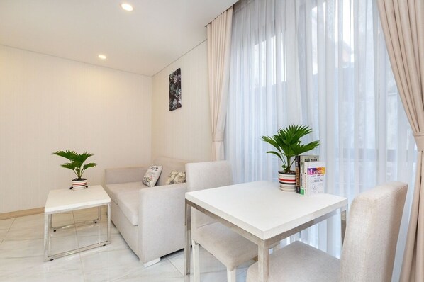 Un salon moderne avec un canapé blanc, une petite table blanche et une plante en pot.