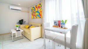 Ein modernes Wohnzimmer mit einer Couch, einem Couchtisch, einem Beistelltisch mit Blumen und einem farbenfrohen abstrakten Gemälde an der Wand.