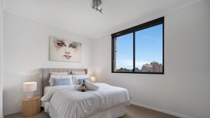 A bedroom with a large bed, a city view, and a painting on the wall. - Central Urban Nest with Pool (Perth)