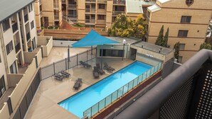 A rooftop swimming pool with a blue canopy, surrounded by lounge chairs and a glass railing. - Central Urban Nest with Pool (Perth)