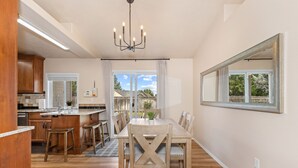 Una cocina moderna con armarios de madera, un comedor con una mesa grande y sillas, y vistas al exterior a través de un ventanal.