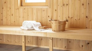 Un banco de madera con un balde de madera y toallas enrolladas.