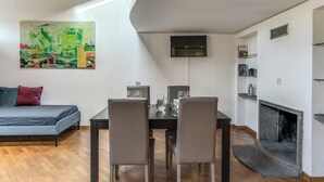 Un salon moderne comprenant une table à manger, deux chaises, un canapé, une cheminée et un tableau accroché au mur.