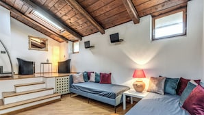Une chambre avec un lit en mezzanine, un canapé-lit, une petite table, une lampe et un miroir.