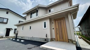 Una casa de dos pisos con entrada principal, un pequeño porche y un camino de acceso.