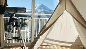 Un telescopio sobre un trípode, una tienda de campaña y una vista de una montaña nevada a través de una ventana.
