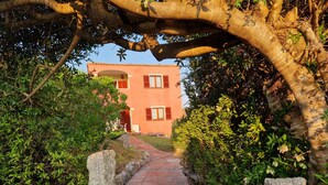 A pathway leading to a building with a red facade and shuttered windows. - Within walking distance of the beautiful Vignola beach, with panoramic terrace. (Vignola Mare)