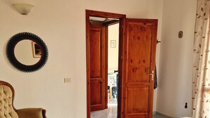 A bedroom with a bed, a chair, and a door leading to another room.