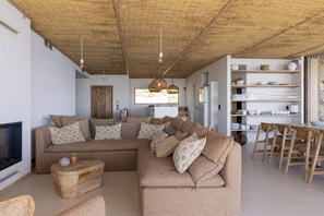 A living room with a sectional sofa, a coffee table, a TV, and a dining area with chairs and a table. - VILLA IPANEMA - New Home Coming Soon, Sleeps 14, Panoramic Sea View (OLMETO PLAGE)