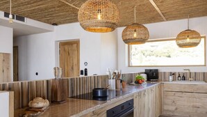 A modern kitchen with wooden cabinetry, a built-in oven, and a large window providing natural light.