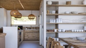 A modern kitchen with wooden cabinets, a dining area with a wooden table and chairs, and a large window providing natural light.