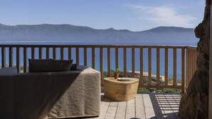 A balcony with a wooden railing, a sofa, and a round wooden table.
