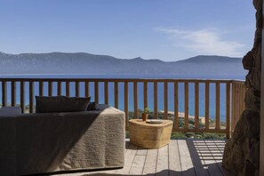 A balcony with a wooden railing, a sofa, and a round wooden table.
