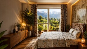 A bedroom with a large bed, wooden furniture, a view of mountains, and potted plants.