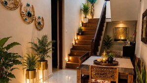 A spacious living area with a wooden staircase, a dining table with chairs, and decorative wall art.