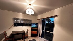 A room with a dining table, chairs, a TV, and a sliding glass door leading to a backyard.