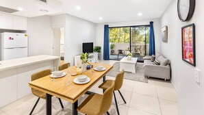 A modern apartment with a dining area, kitchen, living room, and a balcony with a view.