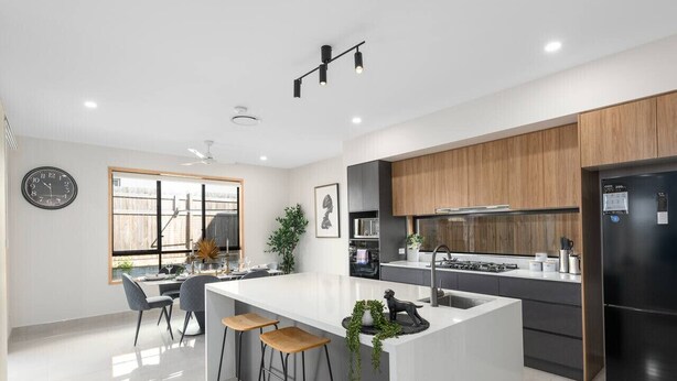 A modern kitchen with a central island, bar stools, and a refrigerator.