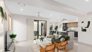A modern living room with a sofa, two wooden chairs, a coffee table, and a TV.