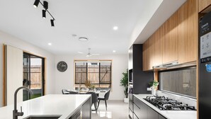 A modern kitchen with a central island, a dining area, and a view of the outdoors.