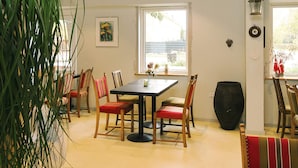 Uma sala de jantar com uma mesa, cadeiras e um vaso grande.