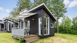 A modern cabin with a deck, large windows, and a covered outdoor seating area. - 4 Person Holiday Park Home in Vipperod (Vipperod)